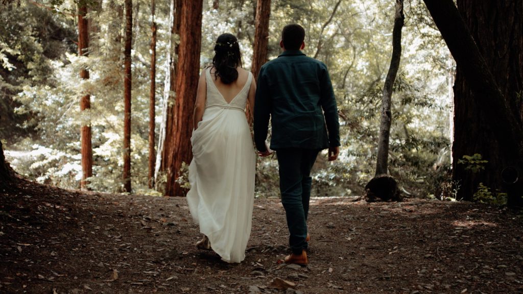 A bride and groom walking in the redwoods on their wedding day.