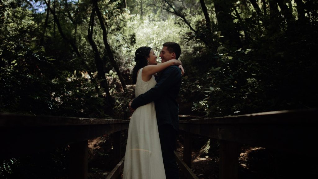 A bride and groom on a bridge in the redwoods on their wedding day.
