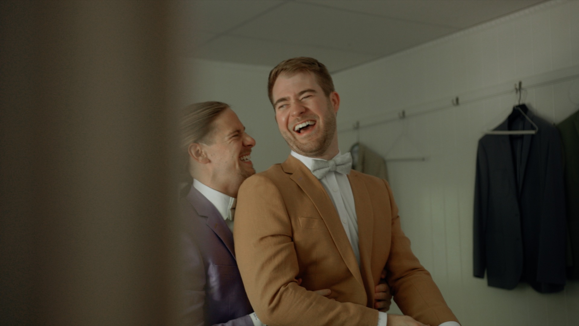 two grooms helping each other get ready at their wedding