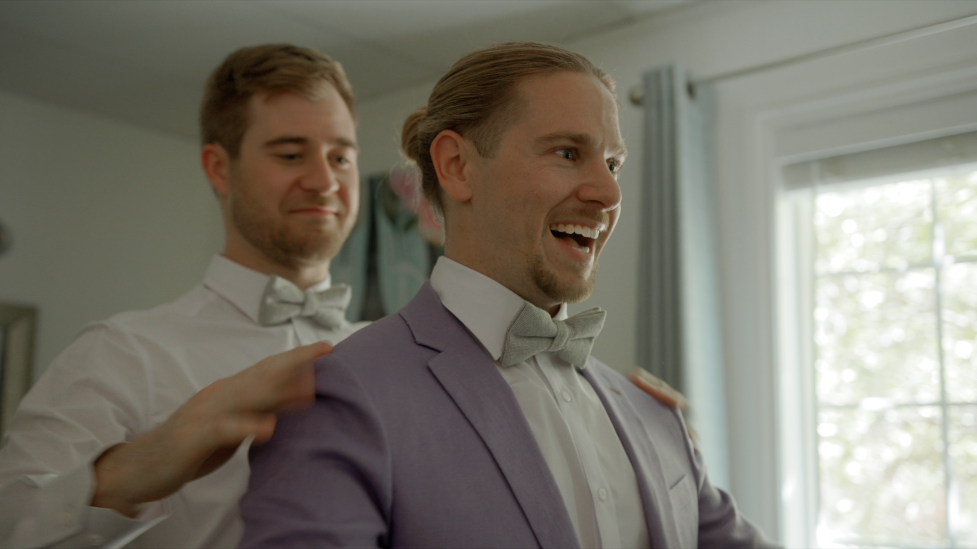 two grooms helping each other get ready at their wedding