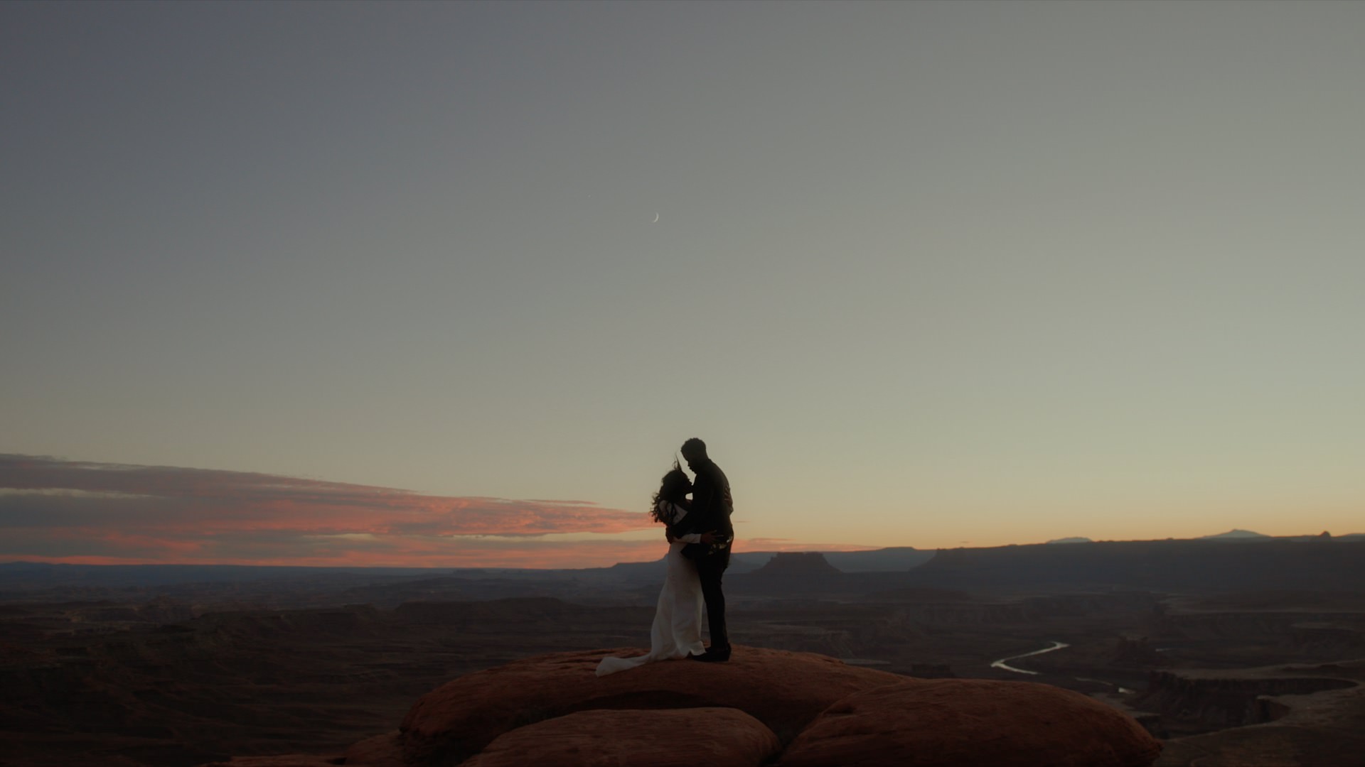a man and woman holding each other at canyonlands national park